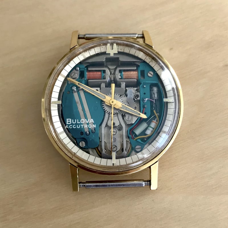 Front display of a vintage wristwatch without a traditional dial, exposing the inner workings of the timepiece.